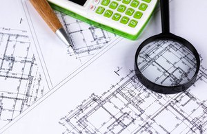 Magnifying glass and calculator over construction drawings during a quality-control review