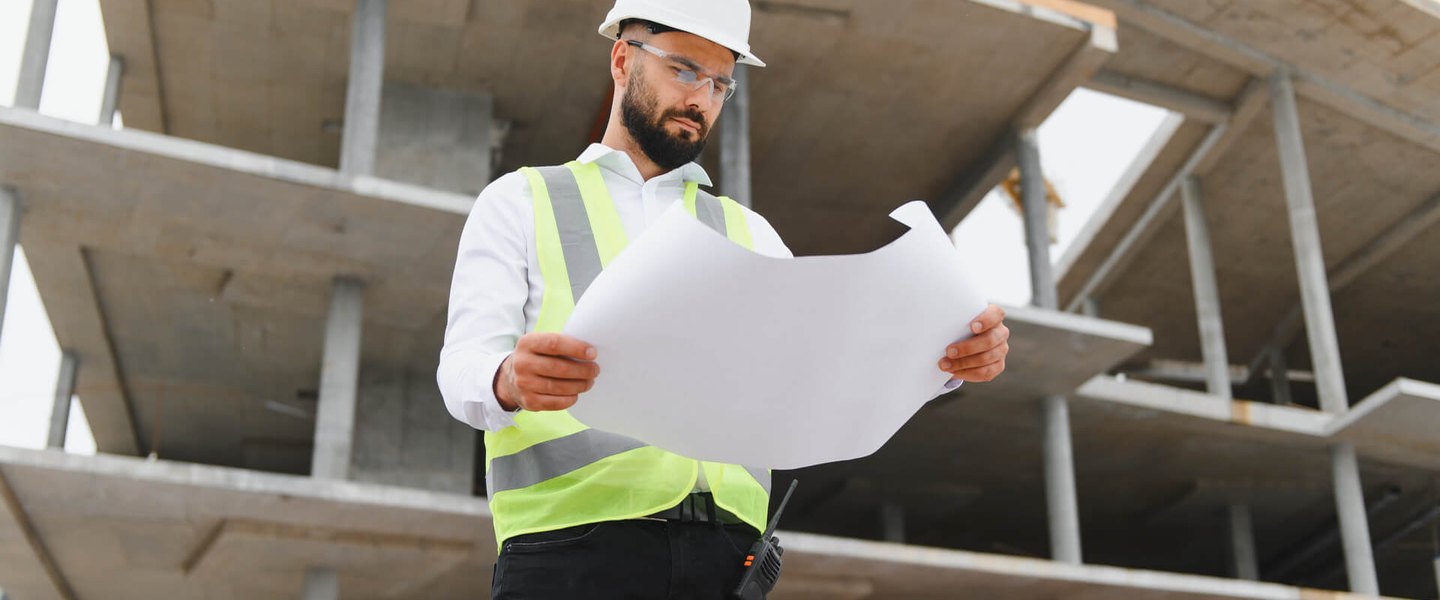 Forensic inspection and report review Construction professional examining blueprints on site during a forensic review