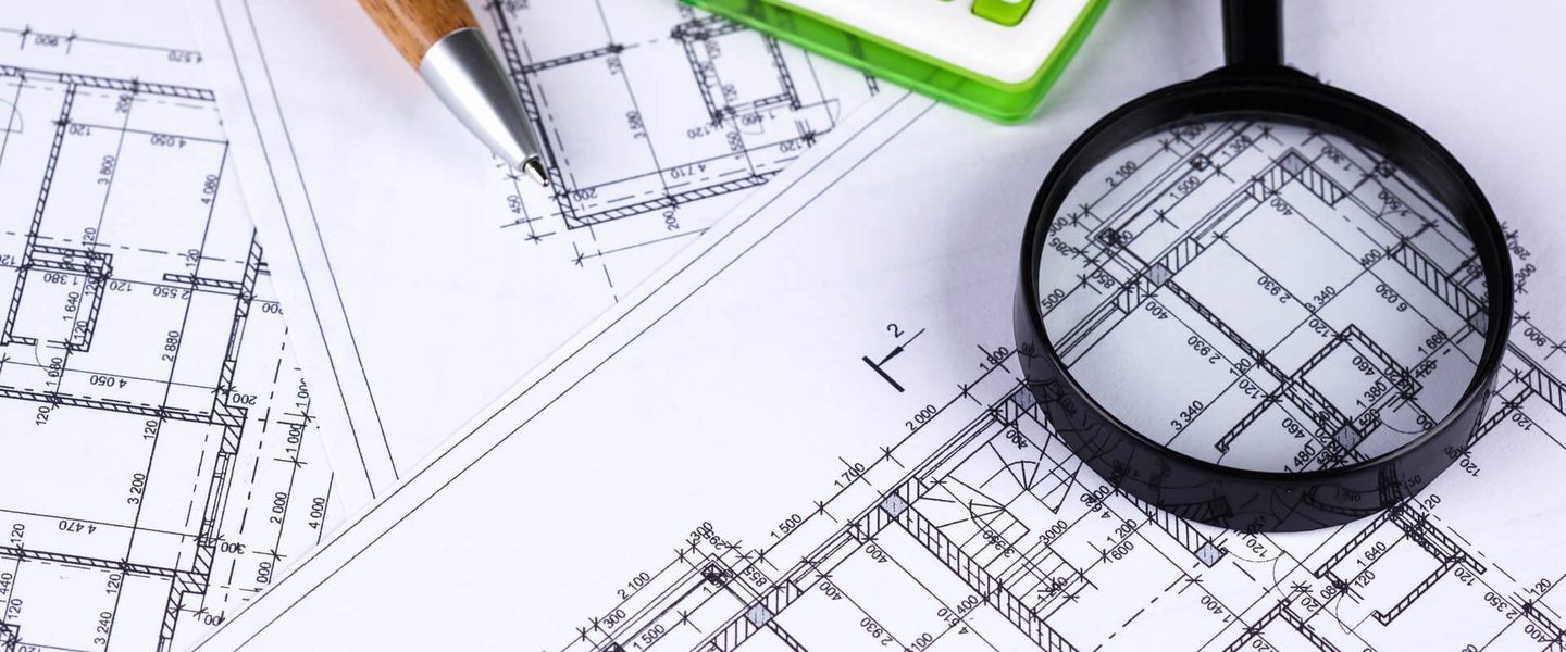 Quality Control and Inspection Magnifying glass over construction drawings during a quality-control review